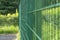 A metal fence made of thin rods painted with green