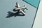 Metal figure of small airplane with shadows on the turqouise and light blue geometry background. Flatlay, top view, layout.