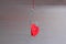 A metal fishing hook hanging on a rope pierced tow hearts of the red cardboard. Concept of love. Valentine`s day