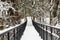 Metal footbridge over the stream, in the winter snowy forest, beautiful winter landscape