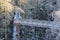 Metal footbridge over the stream, in winter snowy forest, beautiful winter landscape