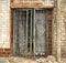 A metal gate in front of an abandoned brick house is locked with a key. Forgotten, abandoned ghost town Skrunda, Latvia.