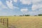 Metal gate leads to large prairie and Texas farm house with storage tower silo in farmyard