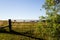 Metal gate and wooden fence post on field on hill