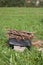 Metal grill with firewood among the green grass in the meadow. Near firewood and grass for lighting