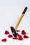 A metal hammer strikes red paper hearts on a white background