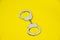 Metal handcuffs isolated on yellow background