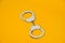 Metal handcuffs isolated on yellow background