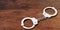 Metal handcuffs on wooden background, 3d illustration