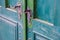 Metal, handmade door handle on green painted wooden door