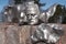 Metal head statue on top of a rock with trees in the background