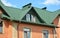 Metal house roof with attic window, roof gutters and brick walls