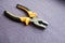 Metal, iron pliers with rubberized yellow-black handles