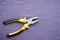 Metal, iron pliers with rubberized yellow-black handles