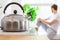 Metal kettle on electric stove. In the background, a young man sits on the windowsill. Good morning concept