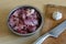 Metal kitchen knife, garlic, cutting board and bowl of raw meat pieces