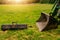 Metal ladle on the grass and one on a green tractor.. Heavy machinery concept. Sun flare in the background. Selective focus