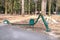 Metal litter bin to keep public recreation spaces clean. Beautiful dense coniferous grove on the background.