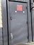 A metal locked delivery door with delivery hours sign