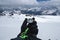 A metal magnetic compass in the hand of a traveler in a black glove against the backdrop of snow-capped mountains