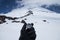 A metal magnetic compass in the hand of a traveler in a black glove against the backdrop of snow-capped mountains