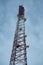 Metal mobile communications tower cell site with antennas close-up against the sky at dusk. Vertical orientation.