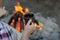 Metal mug in the hands of a tourist, in the woods near the fire.