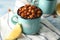 Metal mugs with fried chickpeas and cut lemon on table