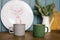 Metal mugs of gray and green are on the countertop of the kitchen, decorated for Christmas and new year. In the background a white