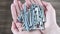 Metal nails, screws, nuts in two palms. New construction equipment. DIY home repair. White human hands show steel screws. Close-up