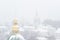 Metal Orthodox cross on the background of winter storm. Snow covered cupola of Lavra in Kiev. Ukrainian landmark.