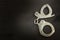 Metal police handcuffs on a dark wooden board. Silver handcuffs. Security concept on wooden background. Closed handcuffs.