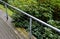 Metal railing on the edge of the park path above the slope. rope stainless steel cable railings. an evergreen rhododendron shrub g