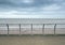 Metal railings on the seafront in blackpool with waves breaking on the beach under a cloudy sky