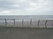 Metal railings on the seafront in blackpool with waves breaking on the beach under a cloudy sky