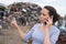 Metal recycling worker gesturing and using mobile phone at junkyard