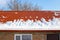 Metal roof in the snow in winter. Descent of snow avalanches from rooftops