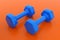 Metal and Rubber Blue Dumbbell Pair Gym Equipment on Orange Background - 3D Illustration