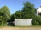 Metal rural cabin surrounded by dense summer vegetation in the countryside