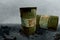 Metal rustic barrels with black liquid like oil drip on dirty World map background. Crude oil market or ecology and chemical