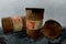 Metal rustic barrels with black liquid like oil drip on dirty World map background. Crude oil market or ecology and chemical