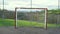 Metal rusty football goal on a sports field with a mesh fence