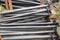 Metal screw supports for the fence are black, stacked in a stack. Construction production