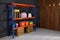 Metal shelving unit with crates and different household stuff near black wall indoors. Space for text