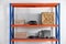 Metal shelving unit with wooden crates and different instruments on light background