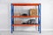 Metal shelving unit with wooden crates and instruments near light wall indoors