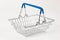 metal shiny basket with grocery handles on white wooden table background. close-up