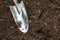 A metal shiny small garden shovel is on freshly plowed ground. Horizontal orientation. Space for text.