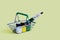 Metal shopping basket with green handles, filled with artistic paints: yellow, green and white colors, tassels, various