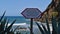 Metal sign above rocky beach Praia da Maiata between agave leaves in village Porto da Cruz in the north of Madeira, Portugal.